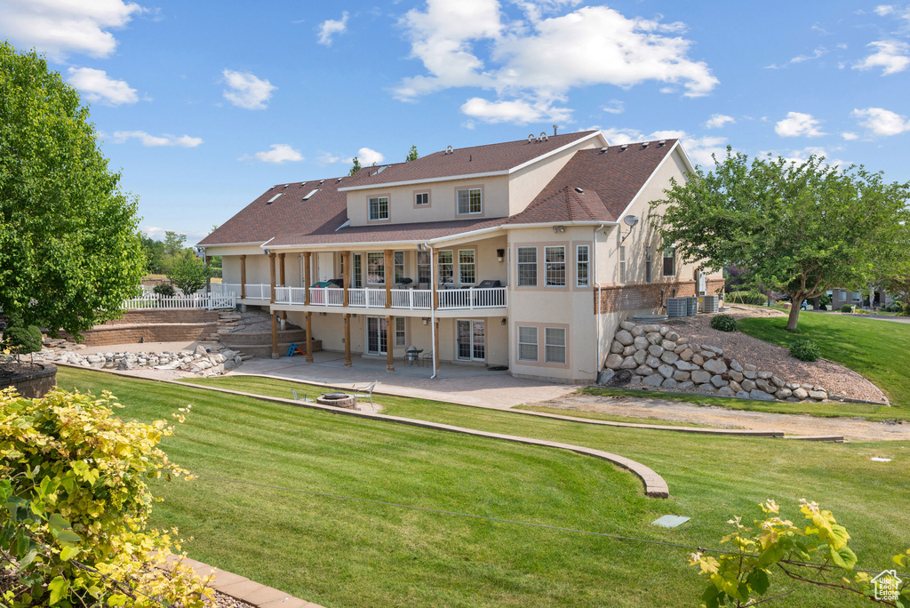 Rear view of house featuring a patio area, a lawn, stucco siding, a deck, and french doors