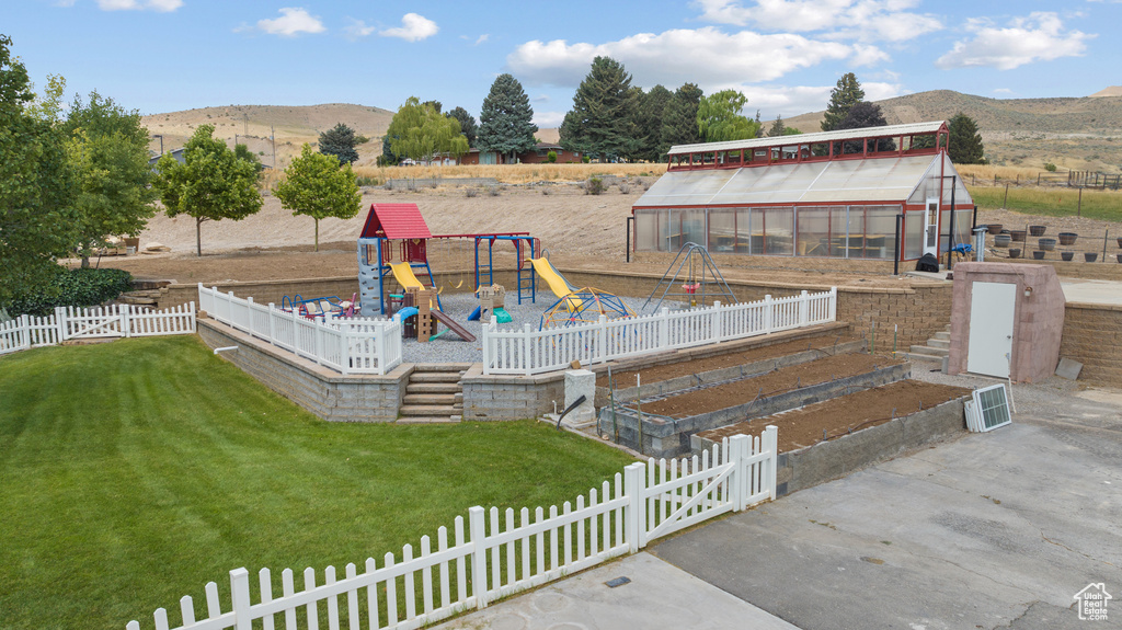 Exterior space with an exterior structure, an outdoor structure, a playground, a mountain view, and a vegetable garden