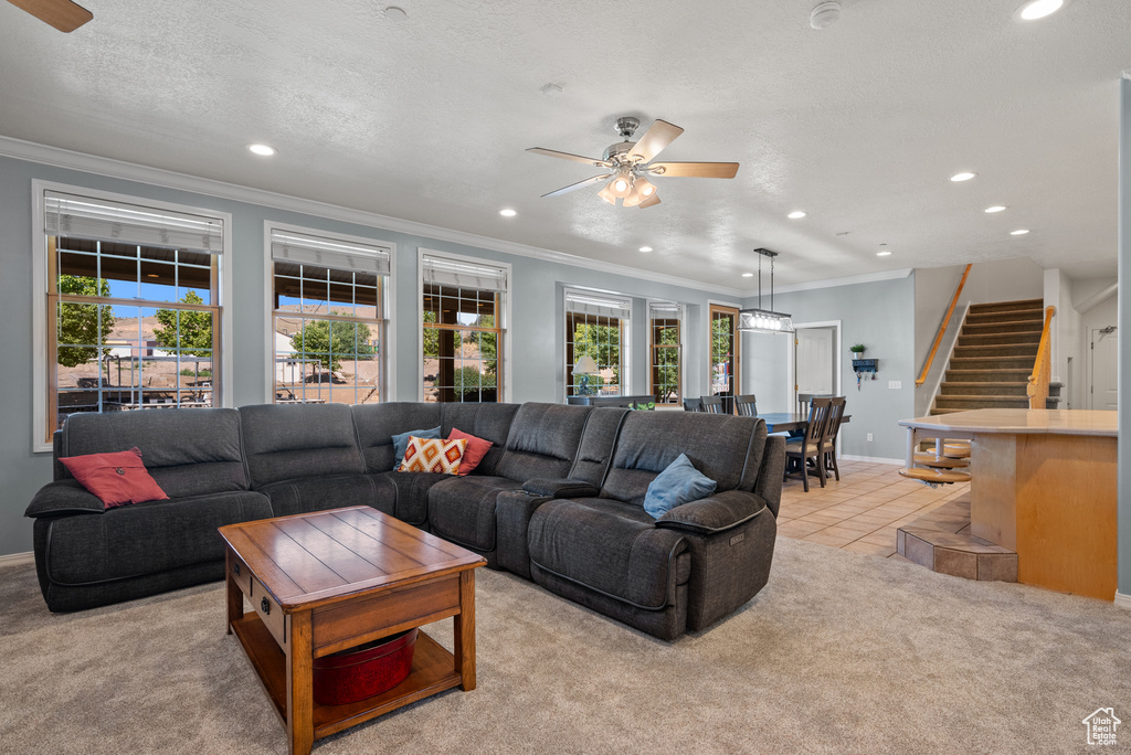 Living area with ceiling fan, recessed lighting, plenty of natural light, light carpet, and crown molding