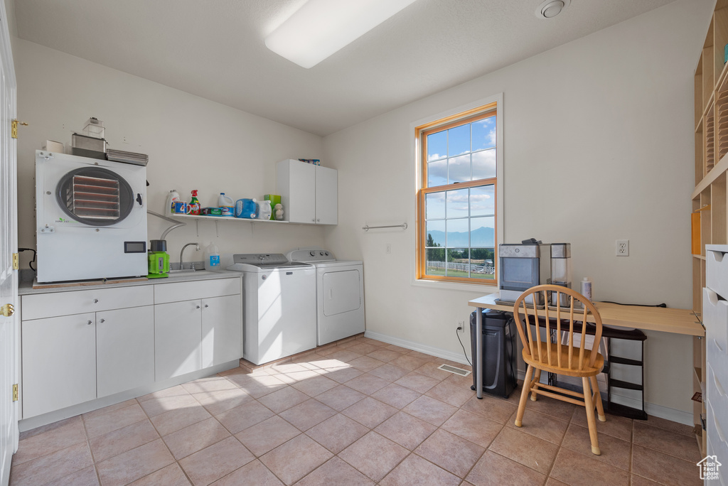 Laundry room with washing machine and clothes dryer, cabinet space, light tile patterned flooring, and an office area