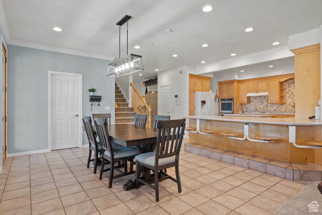 Dining room with light tile patterned floors, recessed lighting, stairway, and crown molding