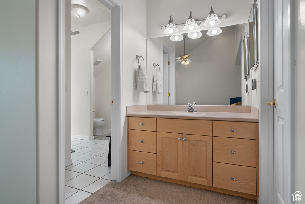 Bathroom with vanity, tile patterned floors, ceiling fan, and lofted ceiling