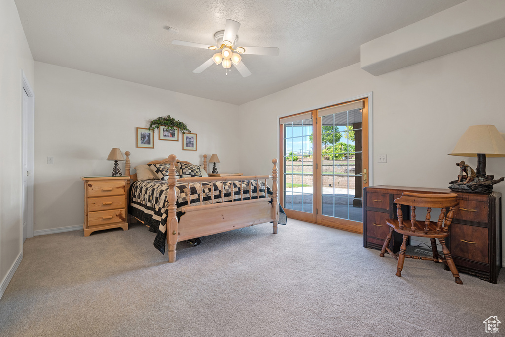 Bedroom featuring access to exterior, light colored carpet, ceiling fan, and a textured ceiling