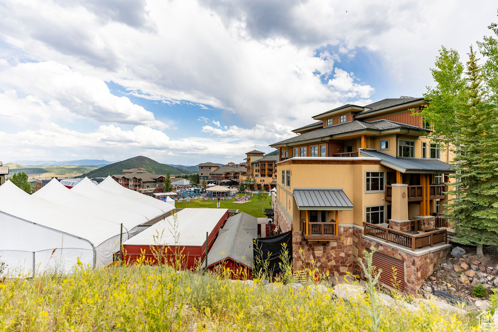 View of side of property featuring stucco siding, a metal roof, a standing seam roof, stone siding, and a mountain view