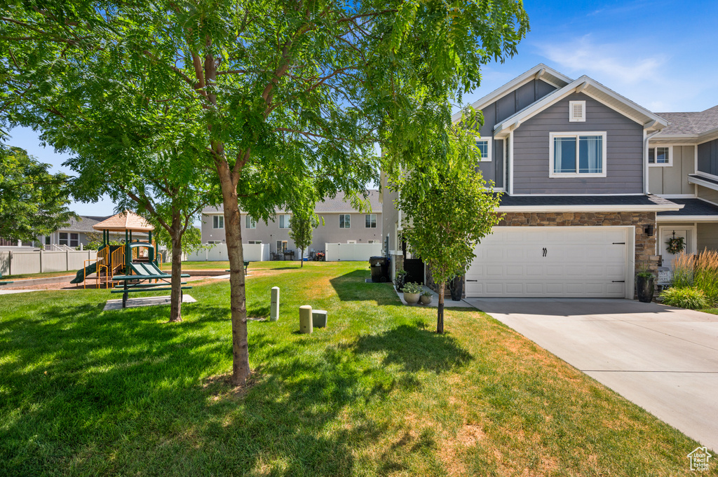 View of front of house with board and batten siding, a playground, concrete driveway, a garage, and stone siding