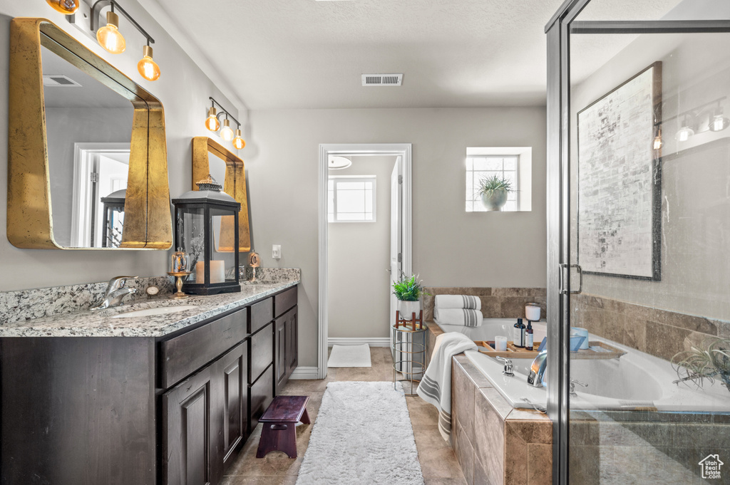 Bathroom with double vanity, a garden tub, a stall shower, and tile patterned flooring