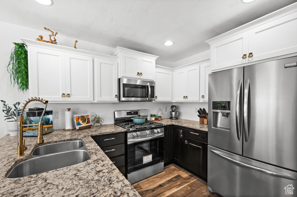 Kitchen featuring stainless steel appliances, white cabinets, recessed lighting, dark wood-style flooring, and light stone countertops