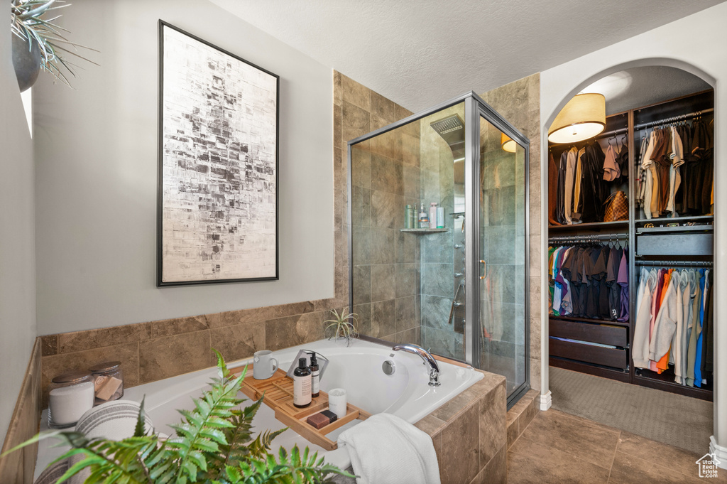 Bathroom featuring a bath, a stall shower, a spacious closet, and tile patterned flooring