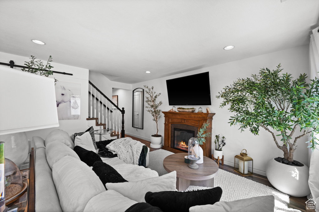 Living area featuring wood finished floors, recessed lighting, stairway, a glass covered fireplace, and a barn door
