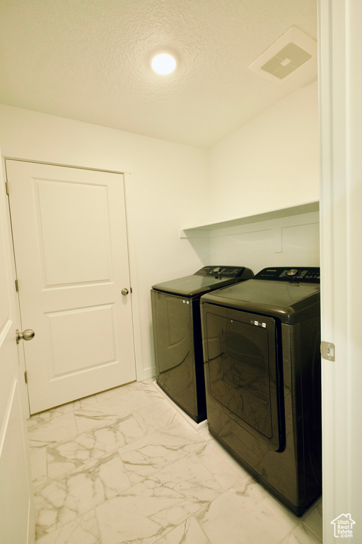 Washroom with washer and clothes dryer, light marble finish floors, a textured ceiling, and recessed lighting