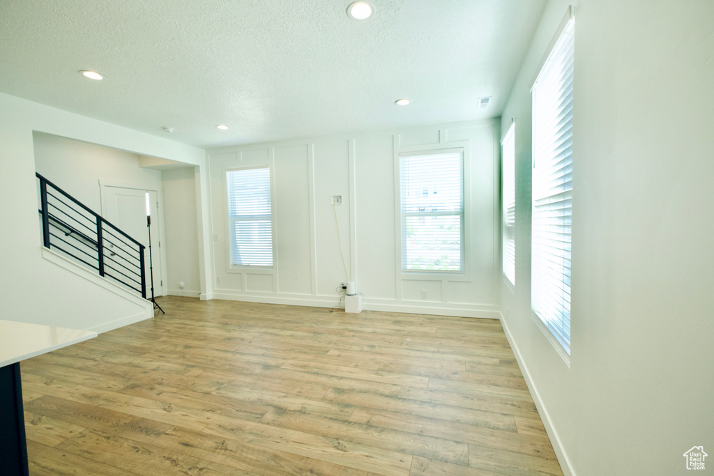 Entrance foyer with stairway, light wood finished floors, healthy amount of natural light, a textured ceiling, and recessed lighting