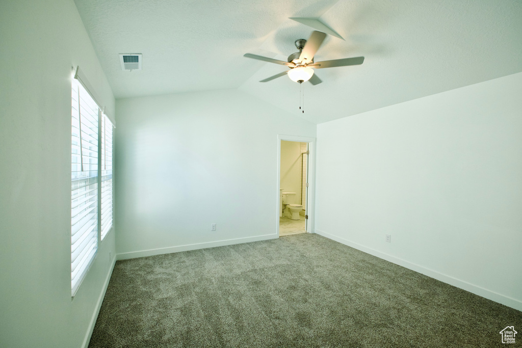 Unfurnished bedroom with multiple windows, carpet floors, lofted ceiling, a ceiling fan, and ensuite bath