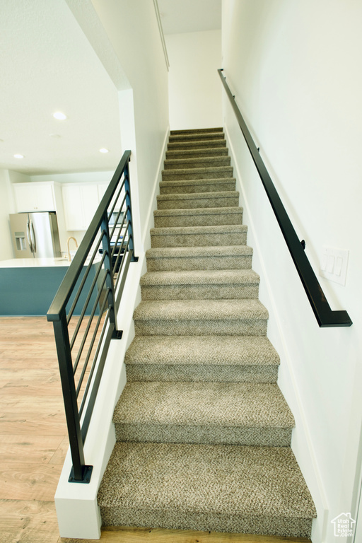 Stairway featuring wood finished floors and recessed lighting