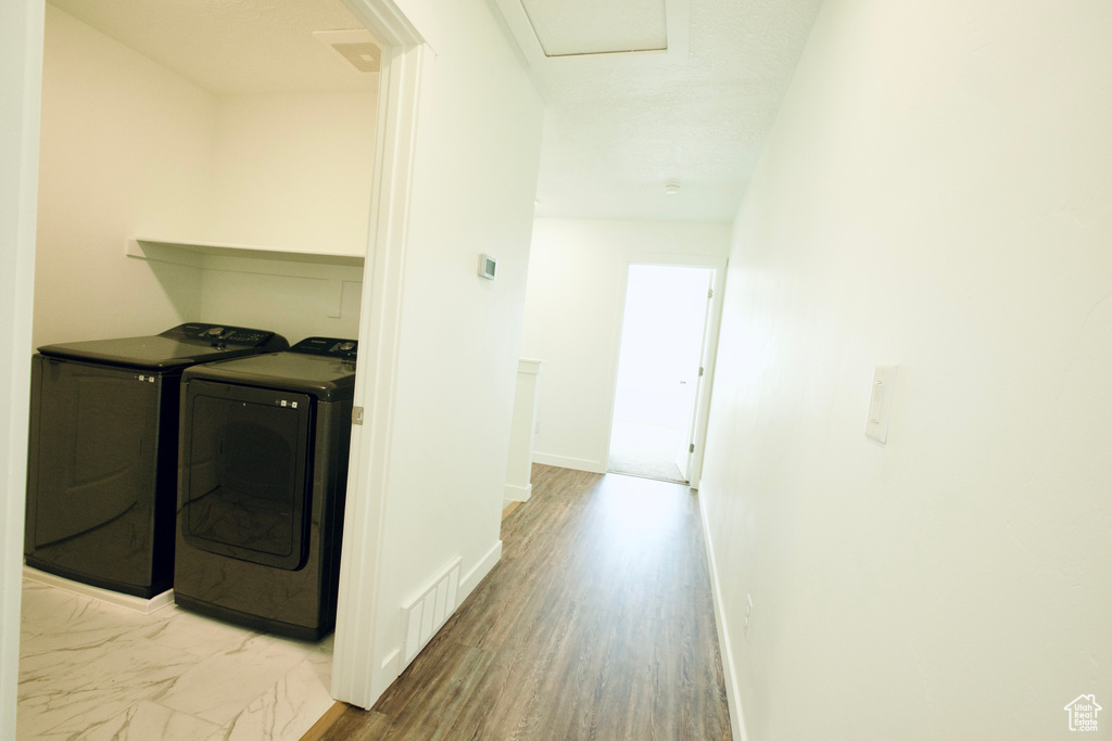 Laundry room with washing machine and dryer and wood finished floors
