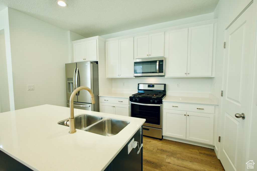 Kitchen featuring stainless steel appliances, dark wood-style floors, white cabinetry, recessed lighting, and a textured ceiling