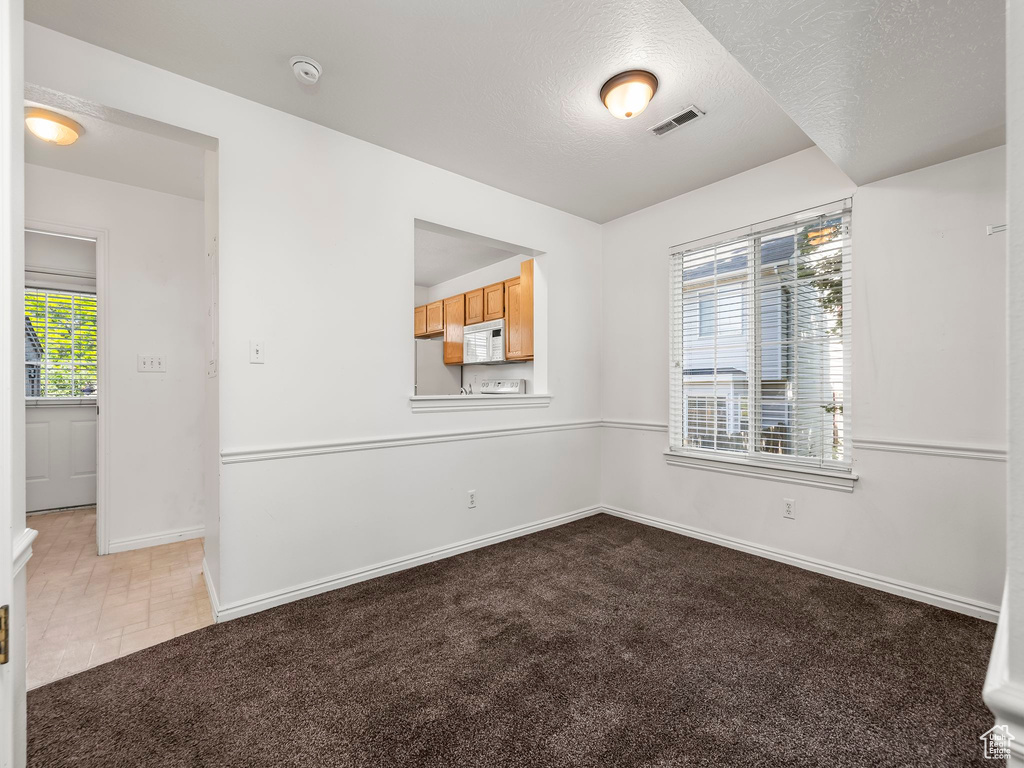 Spare room featuring a smoke detector, a textured ceiling, and carpet
