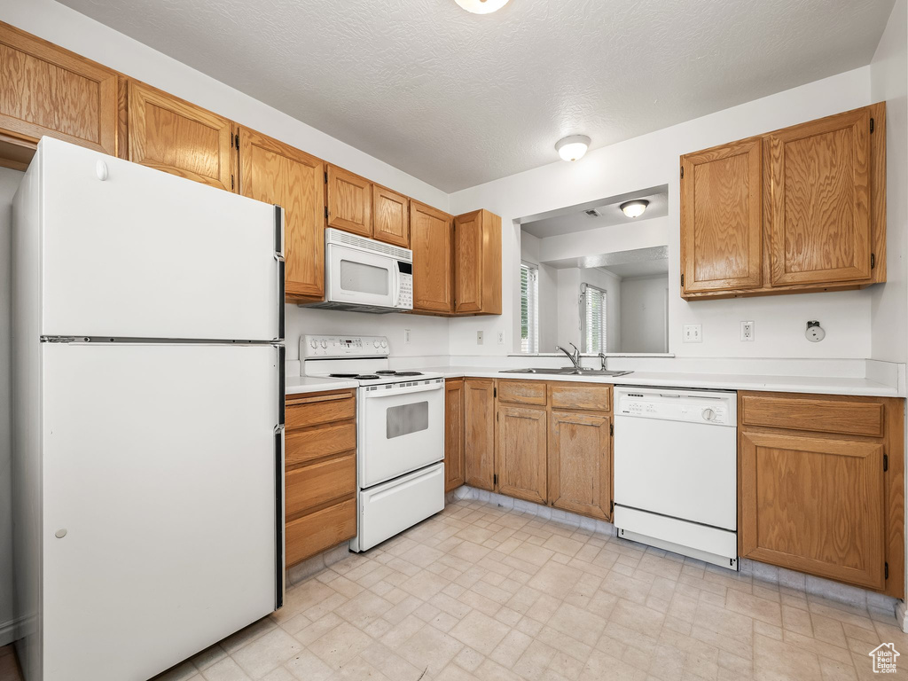 Kitchen with white appliances, light countertops, and brown cabinets