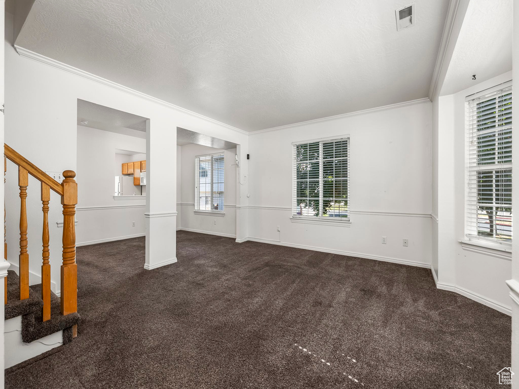 Unfurnished living room with carpet, stairs, ornamental molding, and a textured ceiling