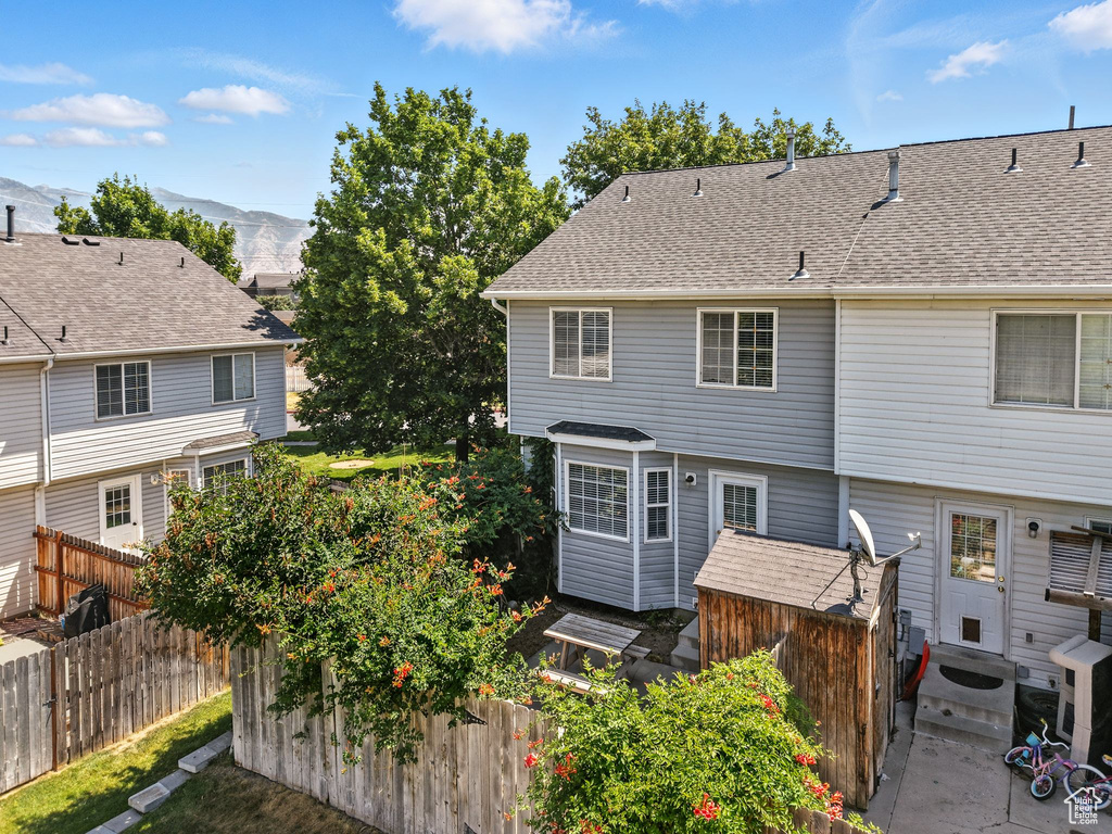 Rear view of property with a mountain view, entry steps, and a shingled roof