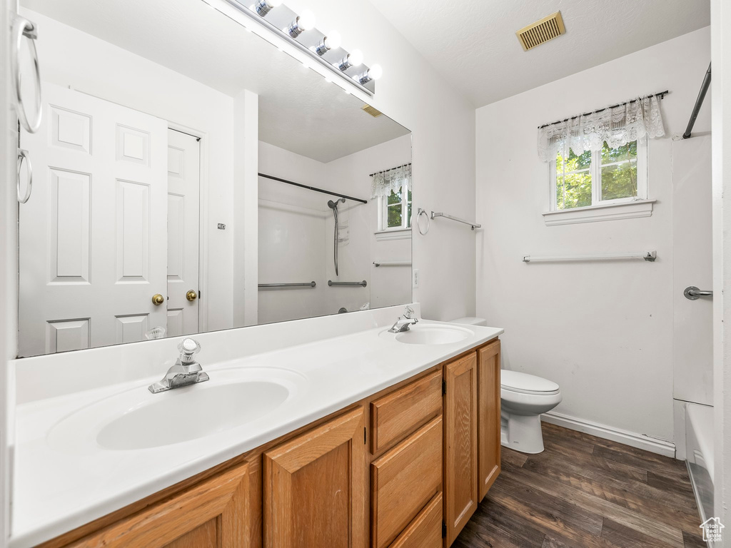 Full bath with double vanity, wood finished floors, and tub / shower combination