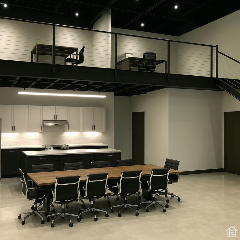 Kitchen featuring under cabinet range hood, light countertops, decorative backsplash, a high ceiling, and dark cabinets