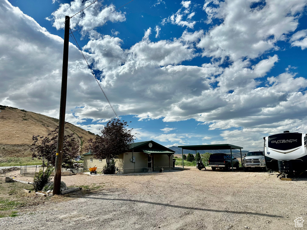 View of front of property with dirt driveway, a detached carport, and a mountain view
