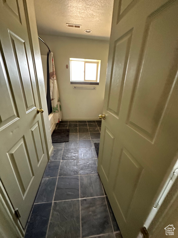 Bathroom with a textured ceiling and shower / bath combo with shower curtain