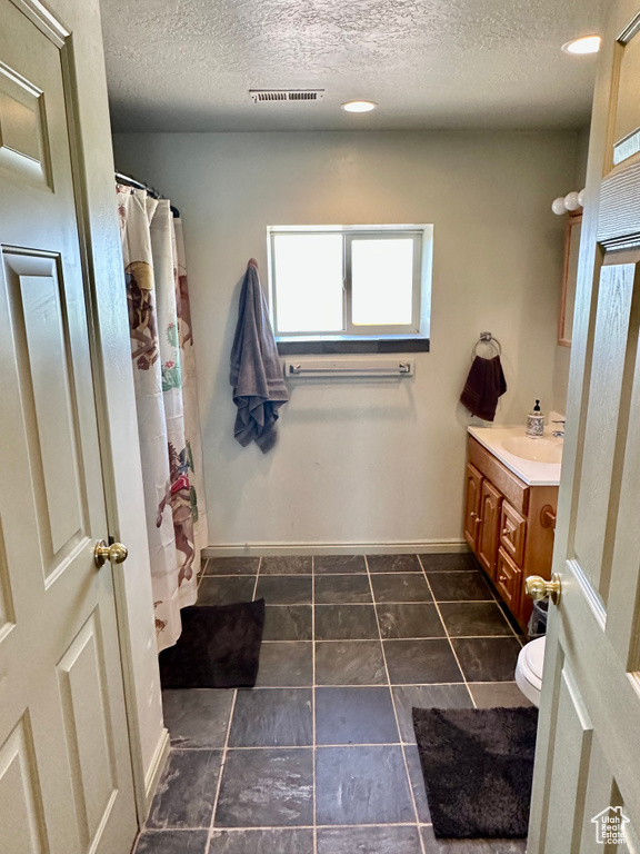 Full bath featuring vanity, a textured ceiling, and curtained shower