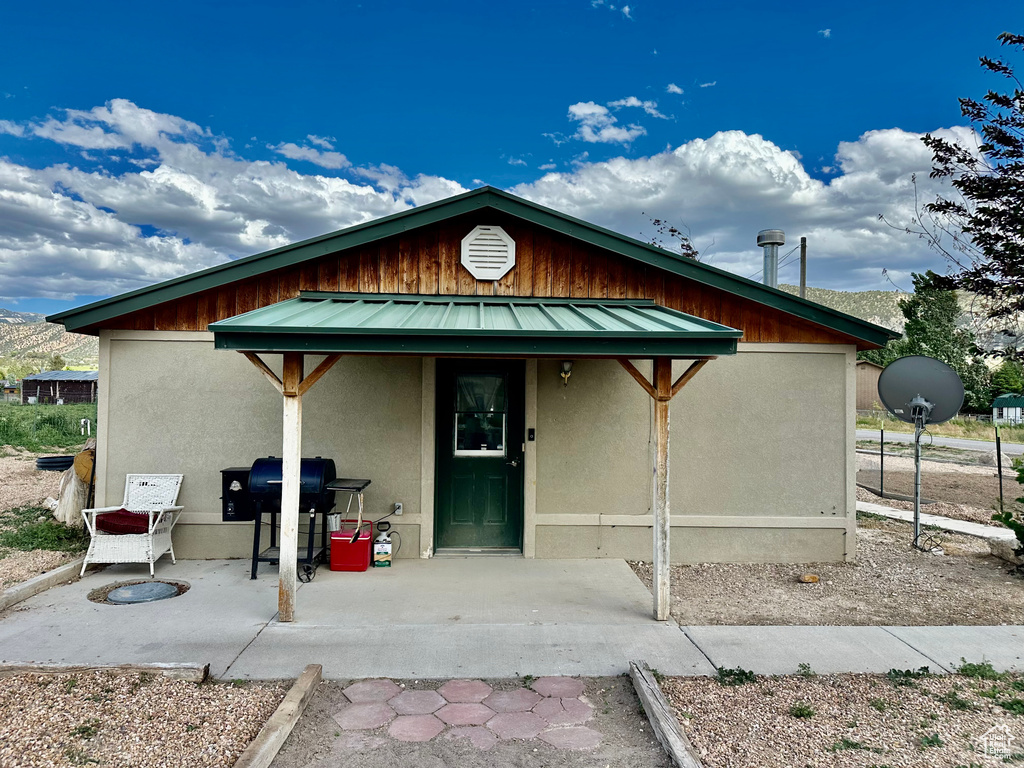 View of front of house featuring stucco siding, a metal roof, and a patio area