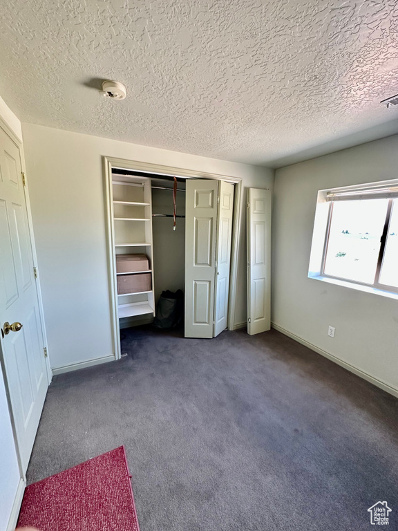 Unfurnished bedroom featuring a textured ceiling, a closet, and carpet flooring