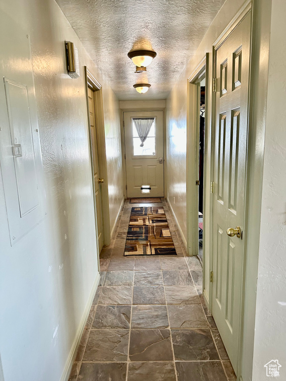 Doorway featuring electric panel and a textured ceiling