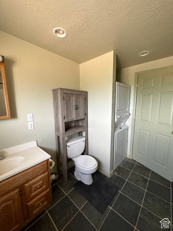 Bathroom with stacked washer / drying machine, vanity, a textured ceiling, tile patterned flooring, and recessed lighting