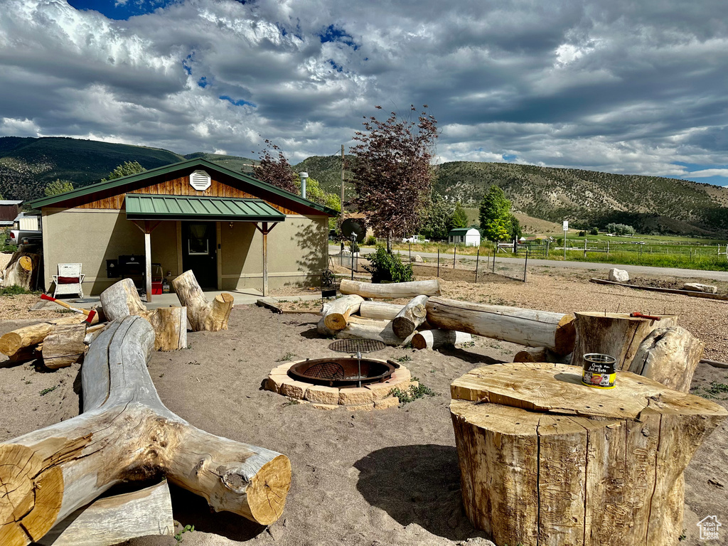 Back of property with a standing seam roof, a mountain view, a metal roof, and a fire pit
