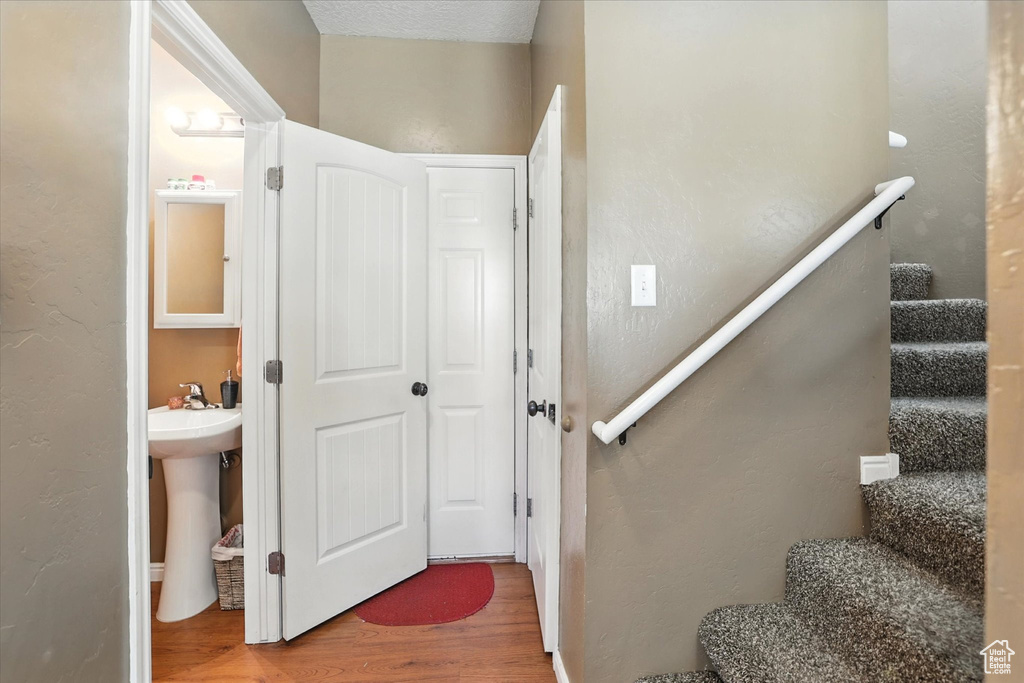 Stairs featuring wood finished floors and a textured wall
