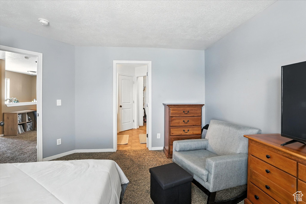 Carpeted bedroom featuring baseboards and a textured ceiling