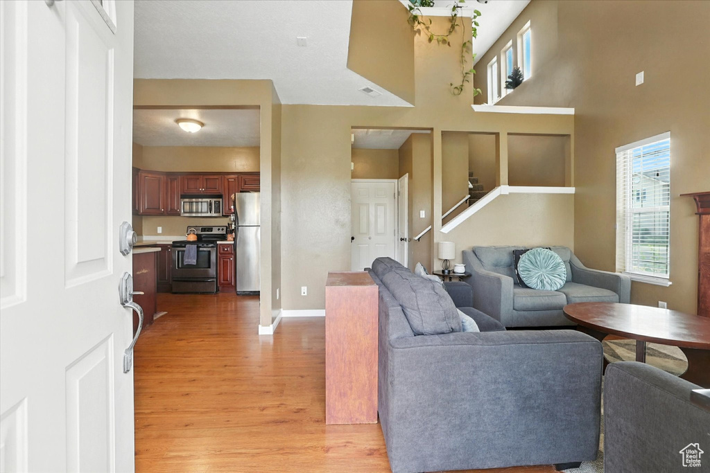 Living room featuring light wood-style flooring, stairs, and a towering ceiling