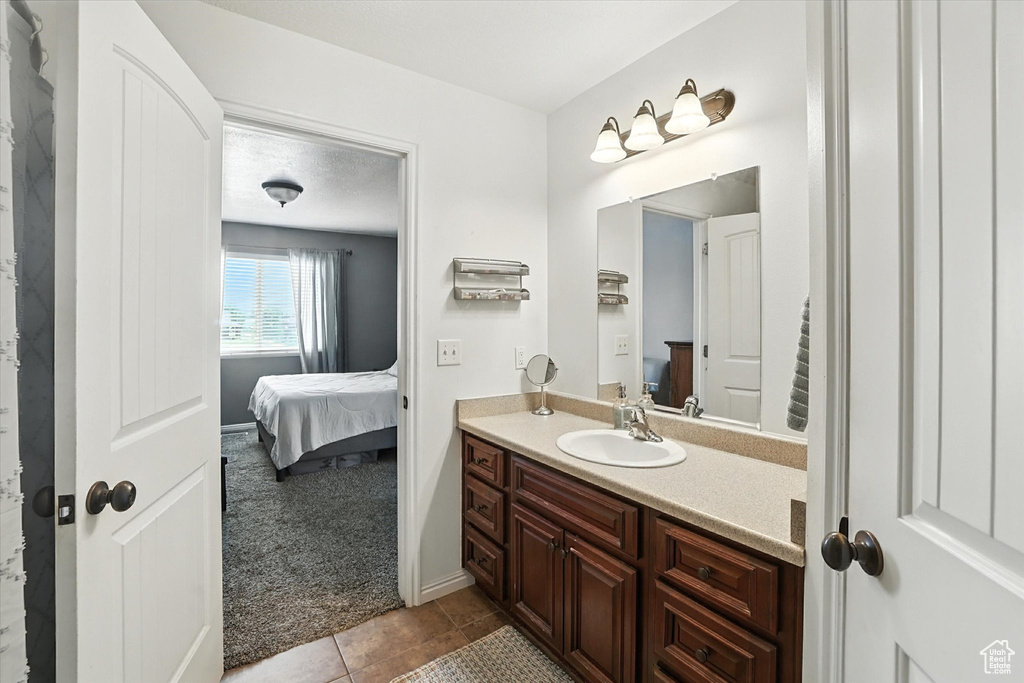 Bathroom with connected bathroom, vanity, and tile patterned flooring