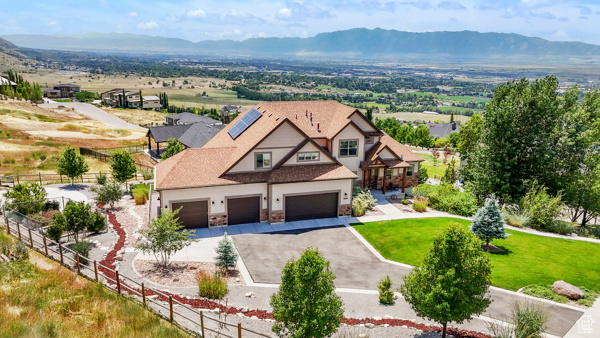 View of front facade with driveway, a mountain view, stone siding, and a garage