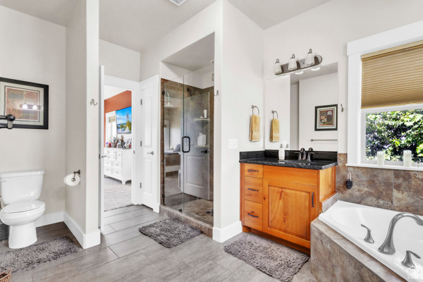 Full bath featuring a stall shower, vanity, wood finished floors, and a bath