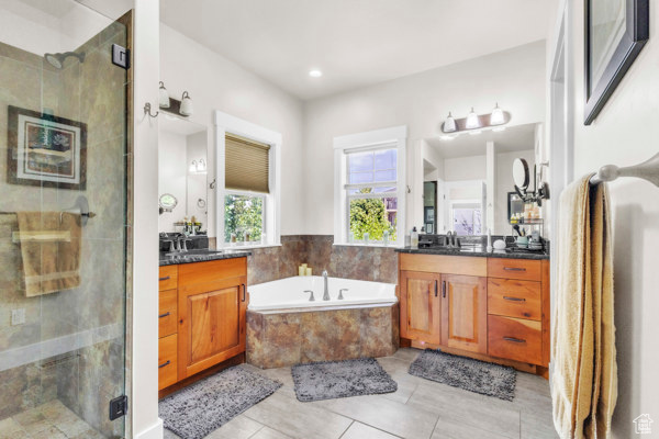 Full bathroom with two vanities, a shower stall, a bath, tile patterned flooring, and recessed lighting