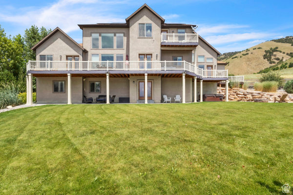 Back of house with stucco siding, a yard, and a wooden deck