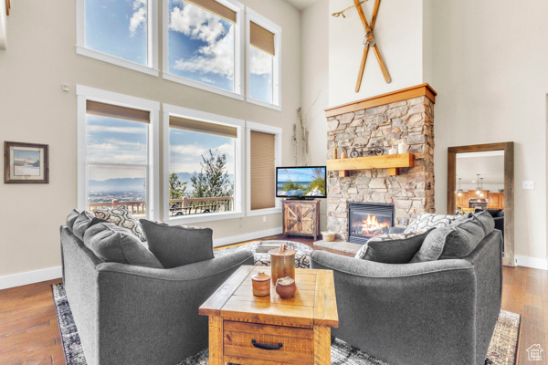 Living area with a high ceiling, a fireplace, wood finished floors, and plenty of natural light