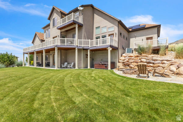 Rear view of house featuring a hot tub, stucco siding, and a yard