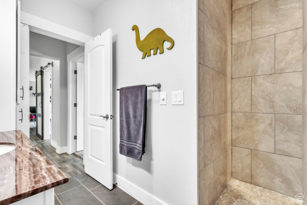 Bathroom with vanity, tile patterned flooring, and tiled shower