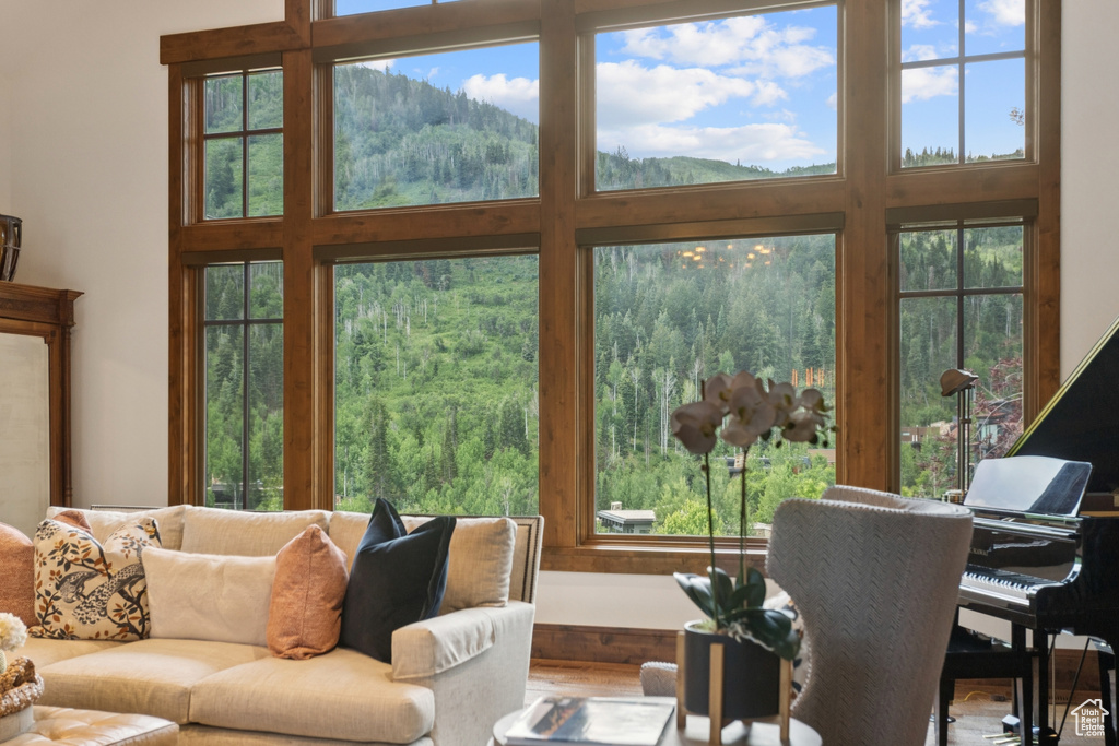 Living area featuring a towering ceiling, a forest view, healthy amount of natural light, and a mountain view