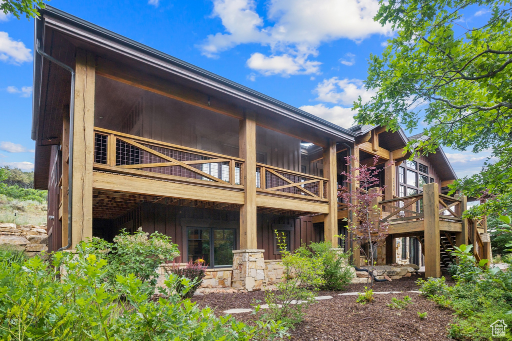 Rear view of property featuring board and batten siding, a wooden deck, and stairway
