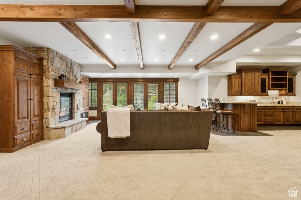 Living area featuring beam ceiling, a fireplace, recessed lighting, and light carpet