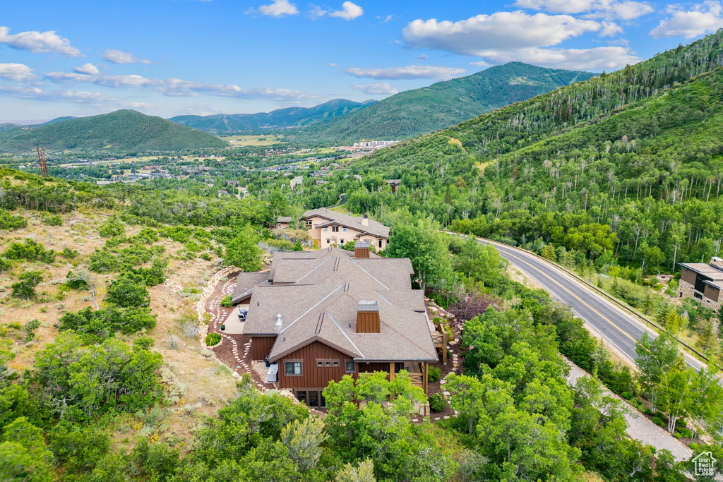 Aerial view of property and surrounding area with a mountain backdrop and a heavily wooded area