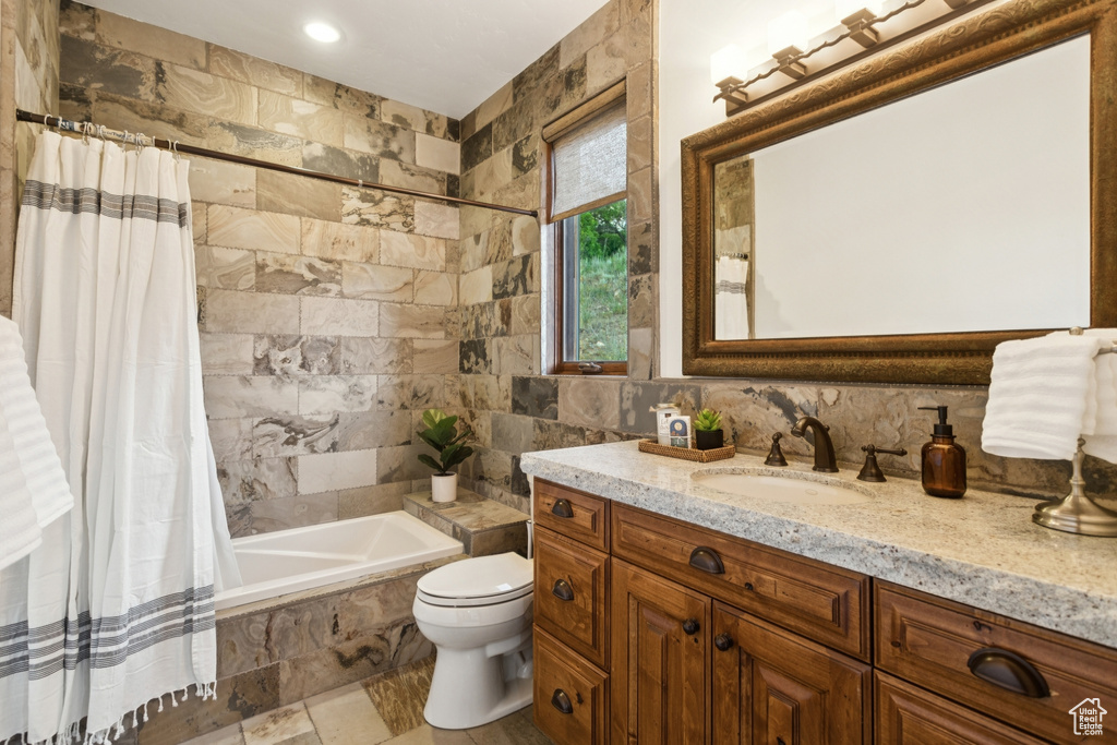 Bathroom featuring tile walls, vanity, and tiled shower / bath