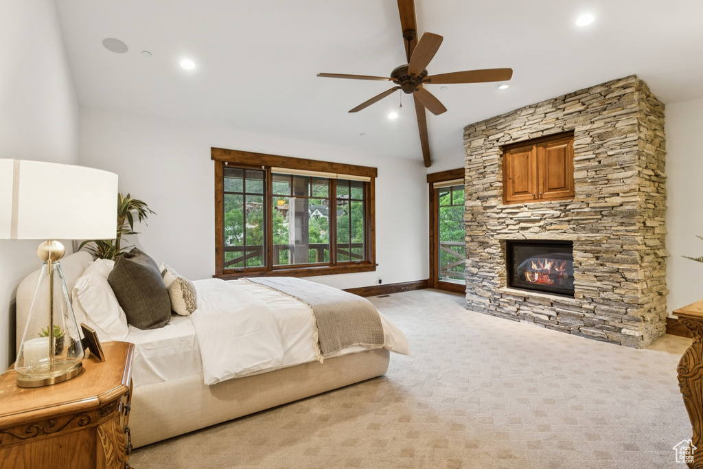 Bedroom featuring a stone fireplace, lofted ceiling, light colored carpet, recessed lighting, and a ceiling fan